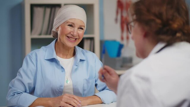 Mature woman with cancer visiting doctor in hospital listening about recovery