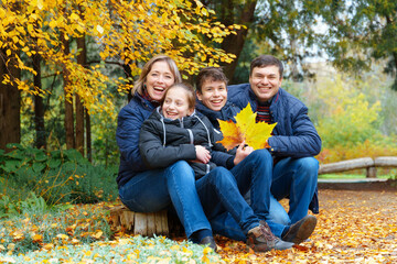 family relaxing outdoor in autumn city park, happy people together, parents and children, they talking and smiling, posing near yellow birch leaves, beautiful nature