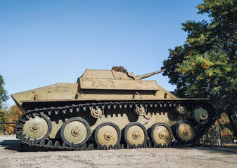 An old Soviet model of the T-70 tank stands against the background of trees and sky. Light armored...