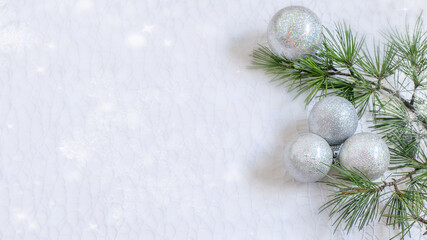 Fototapeta na wymiar Christmas light background with christmas tree branch and silver spheres.
