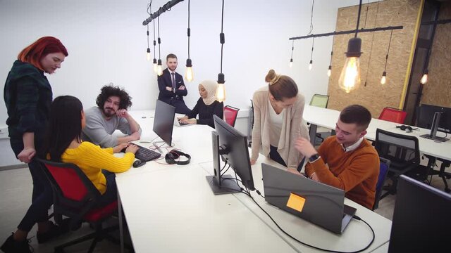 Startup business and entrepreneurship problem solving. Young AI programmers and IT software developers team brainstorming and programming on desktop computer in startup company share office space