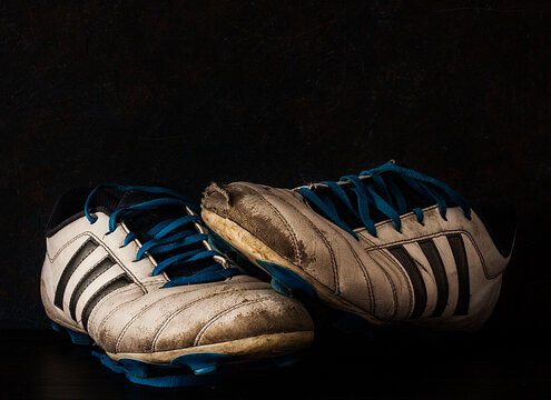 BOTAS DE F&Uacute;TBOL ROTAS Y DESGASTADAS SOBRE FONDO OSCURO