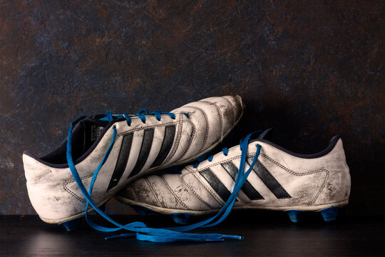 BOTAS DE F&Uacute;TBOL ROTAS Y DESGASTADAS SOBRE FONDO OSCURO