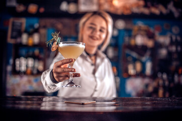 Charming girl bartender decorates colorful concoction in the night club