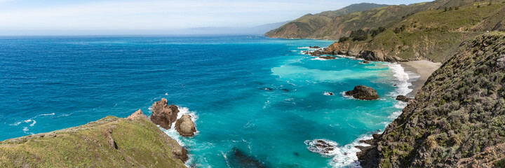 The perfect and serene American, USA west coast in the summer time on a beautiful clear, blue sky day. Turquoise ocean, sea water hanging below giant cliff faces with waves crashing on shoreline.  © Scalia Media