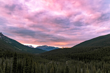 Pink purple sunset overhanging wilderness below in Banff National Park in summer summertime with...