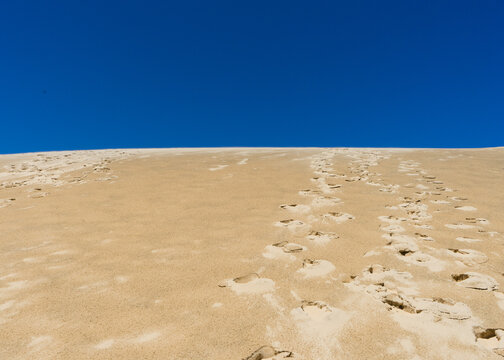 Sand Dune With Footprints And Blue Sky Above