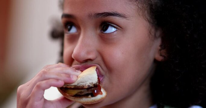 Little girl eating burger. Child taking a bite of hamburger