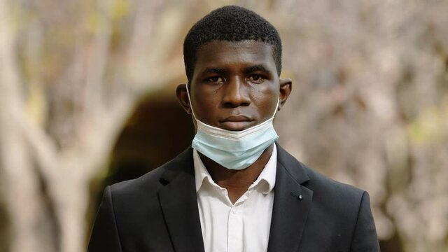 covi19, depression - black man with the mask pulled down stares at camera