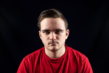 Young man in casual t-shirt standing against isolated dark background