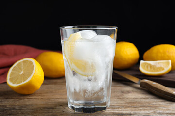 Soda water with lemon slices and ice cubes on wooden table