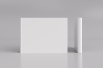 Two hardcover horizontal or landscape white mockup books standing on the white background. Blank front cover and spine of book.
