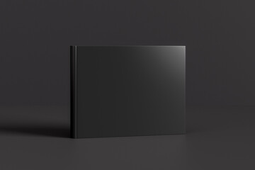 Hardcover horizontal or landscape black mockup book standing on the black background.