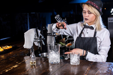 Girl barman makes a cocktail on the taproom
