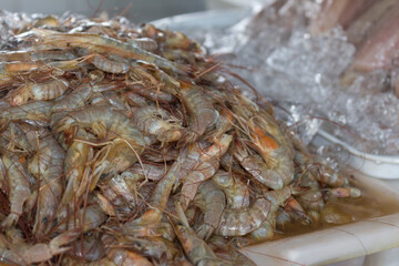 Fresh prawns on ice at the fish market. Raw shrimp with shell and head. Photograph of fish market and fishmongers. Seafood.