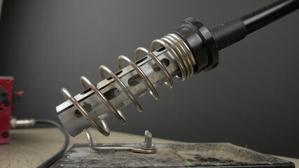 soldering station for soldering electronics, the soldering iron stands on a tripod and smoke from...