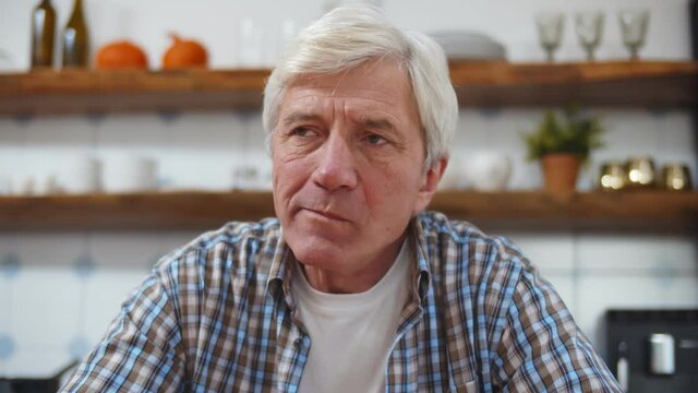 Portrait Of Senior Man Eating Donut With Coffee In Kitchen