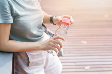 Close up hands of a beautiful wellbeing woman hold a personal reusable / durable clear plastic bottle with pure fresh water inside. Sustainable, Eco friendly, Refuse one-time use plastic, Zero waste. 