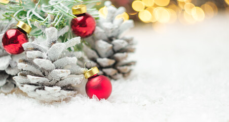 Pine cones and Christmas red balls on the snow. Winter decoration with copy space.