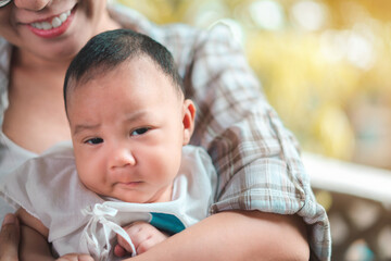 Young asian woman holding a newborn baby in her arms and baby look at camera, Selective focus.