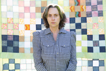 woman in plaid shirt in front of handmade quilt