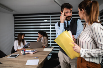 Group of four business people working together in their office on important project. They are talking and analyzing their business plan together.
