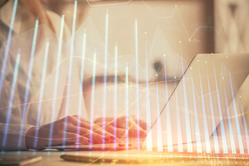 Double exposure of woman hands working on computer and forex graph hologram drawing. Financial...