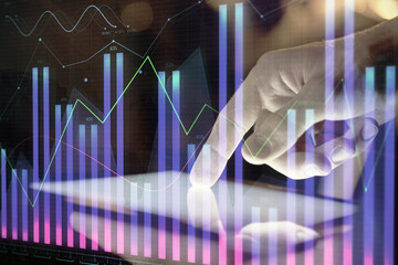 Double exposure of man's hands holding and using a digital device and forex graph drawing. Financial market concept.