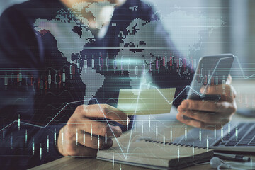 Double exposure of man's hands holding and using a phone and financial graph drawing. Analysis concept.