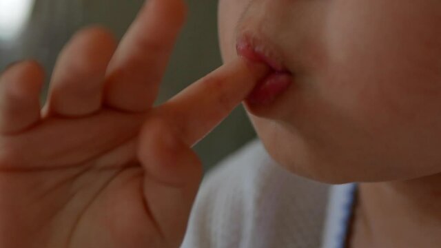 A little toddler sucking his finger at home.