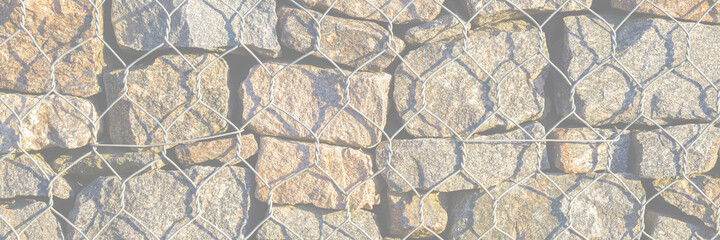 Wall of stones held by a metal mesh. Wide panoramic texture for background and design.