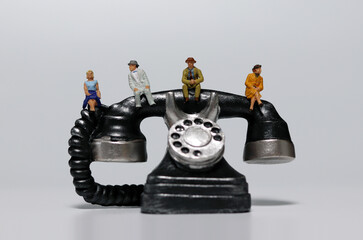 Miniature people sitting on miniature phones. Concepts that recommend non-face-to-face meetings.
