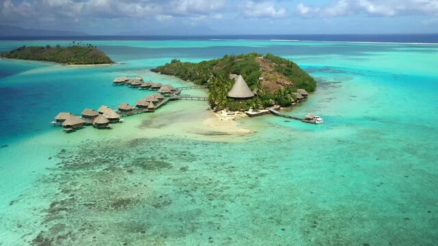 Drone Tahiti aerial view 4k. Remote island in clear blue water lagoon, coral reef. Bora Bora, French Polynesia. Exotic travel vacation getaway, romantic honeymoon destination.