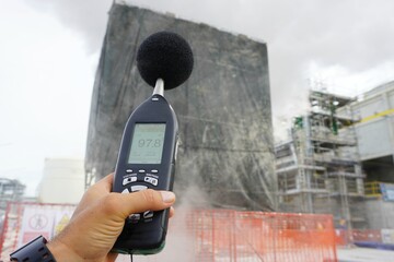 Hand of Environmental officer holding to use sound level meter for monitor is part of the...