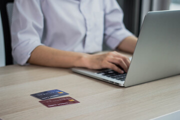 Asian women are shopping online on laptops and using 
credit card to pay.