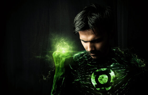 Man In Superhero Costume With Green Light Against Black Background