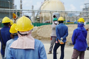 (Focus on the safety helmet) Construction worker in a safety meeting on morning talk before work at oil & Gas factory or Chemical plant under construction site.