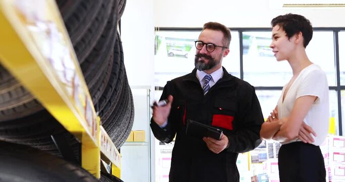 Salesperson and menager explaining the quality of the product to the woman customer. maintenance and auto service garage concept. Saleman showing wheel tires