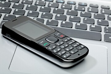 mobile phone on top of a laptop