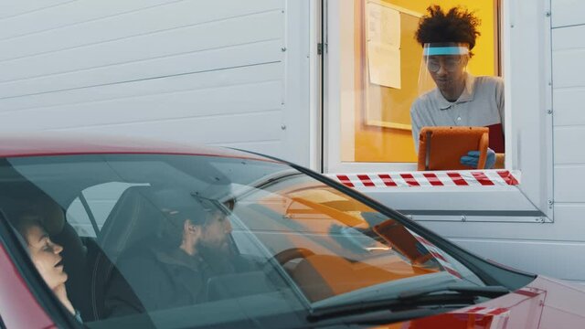 Couple in car ordering takeaway meal at drive thru restaurant