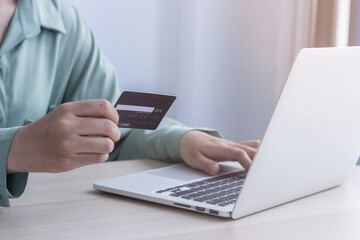 Asian business women are keying in their credit card details to pay online. She is in the office.