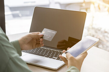 Asian business women are holding credit cards and mobile phones to spend money online. She is in the office.