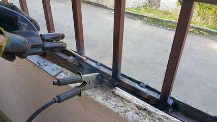 The welder performs semi-automatic electric arc welding. Welding of a metal structure. Working labor. Production and construction.