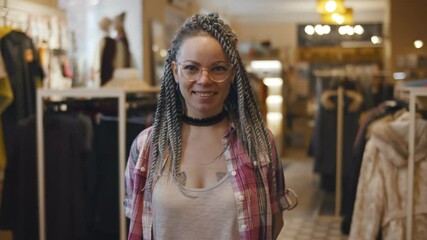 Attractive female shop assistant in eyeglasses is looking at camera and smiling