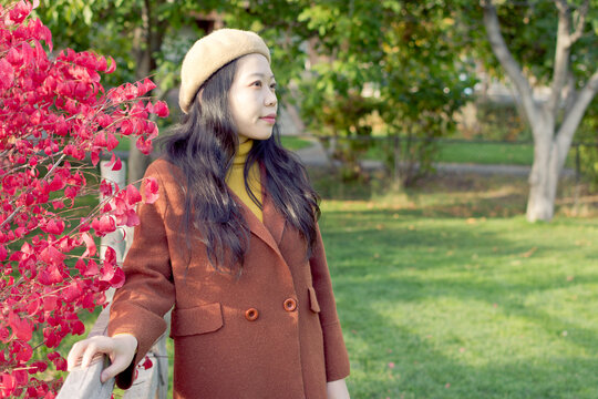 Young Asian Woman Wearing Fall / Autumn Attire Leaning By A Fence