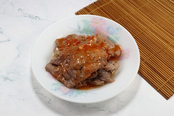 Grilled pork seasoning with red spicy herbal sauce on the plate. Famous appetizer menu in Asia restaurant. 