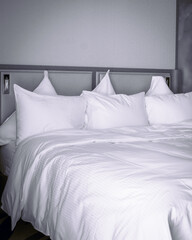 Fototapeta na wymiar Grey Monochrome image of bed with white sheets. Corona virus patients luxury hotel accomodation concept. 2020