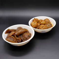 Group photograph of indian pickles or achar like amla pickle and lemon pickle, aavla and Nimbu ka achar sarved in white ceramic bowl, selective focus