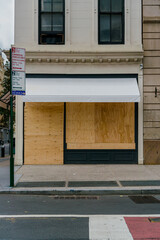 NYC retailer small business boarding up their storefronts with plywood over Broadway building in...
