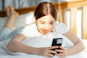 Fototapeta na wymiar Beautiful Asian woman using her phone when she just wakes up